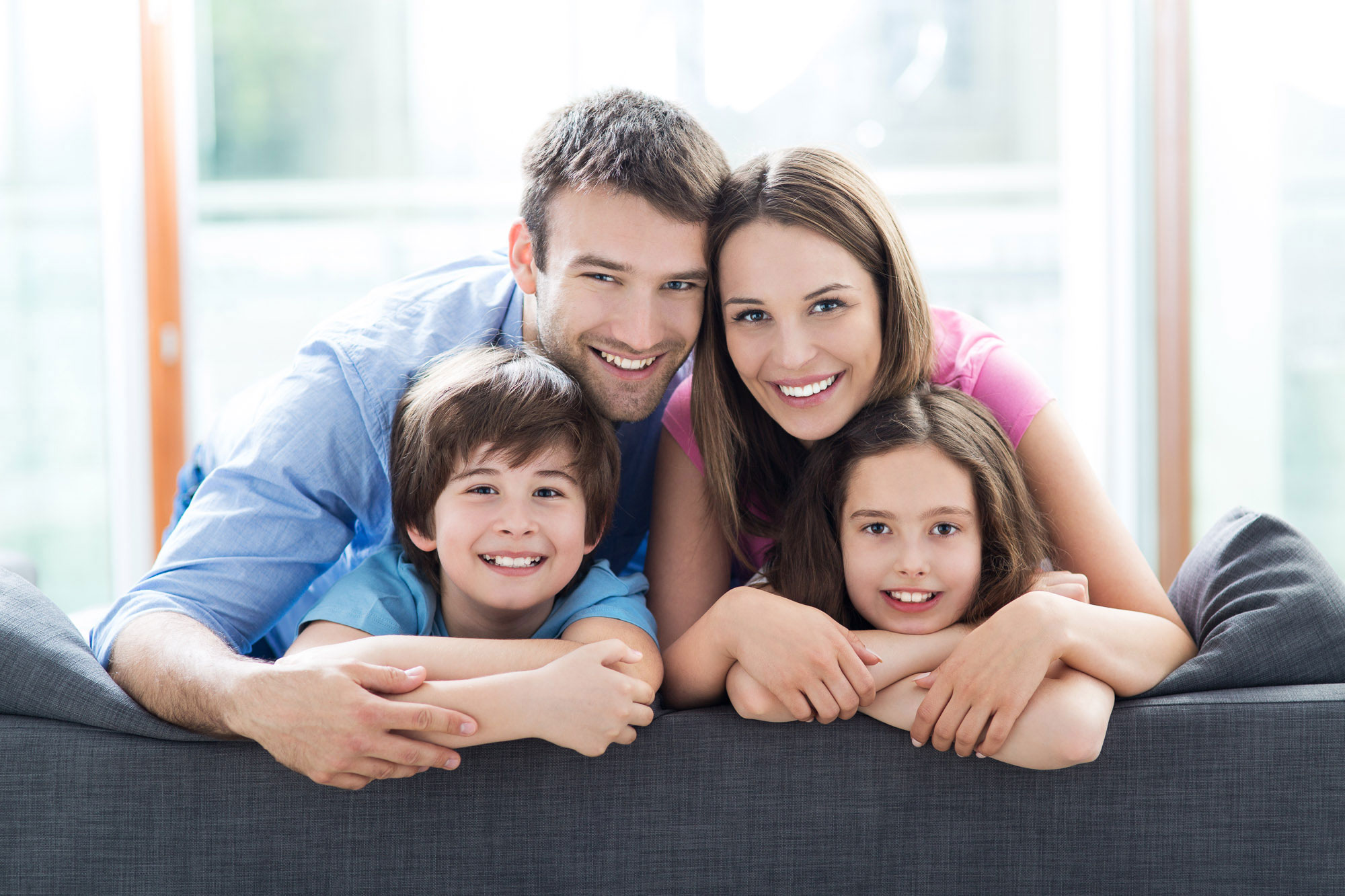 family on couch showing teeth smiling.